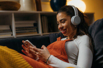 Side view of a young woman relaxing at home with her phone