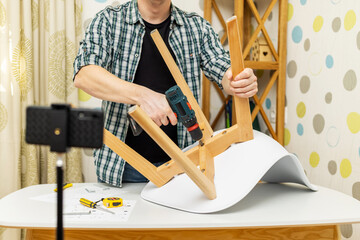 Handyman shows assembling chair, shooting video instructions on smartphone