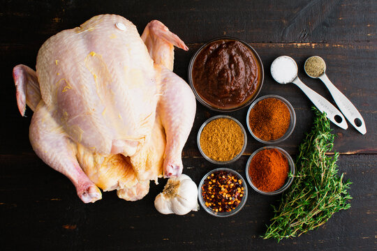 Apple Butter Roasted Chicken Ingredients on a Wooden Table: Raw chicken, apple butter, and spices on a dark wood background