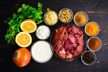 Chicken Liver Curry Ingredients on a Dark Wood Background: Raw chicken livers, Indian spices, and other ingredients on a wooden table
