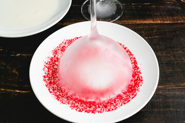 Rimming a Chilled Martini Glass with Sprinkles: Upside down cocktail glass in a plate full of red...