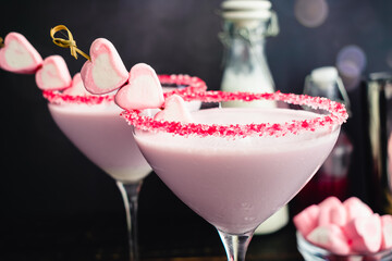 Raspberry and White Chocolate Valentine Cocktail: Pink cocktail in a martini glass rimmed with sprinkles and garnished with heart marshmallows