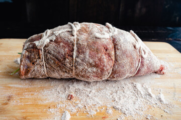 Prepped Stuffed Flank Steak Dusted in Flour: Raw beef pounded thin, stuffed with filling, and tied...