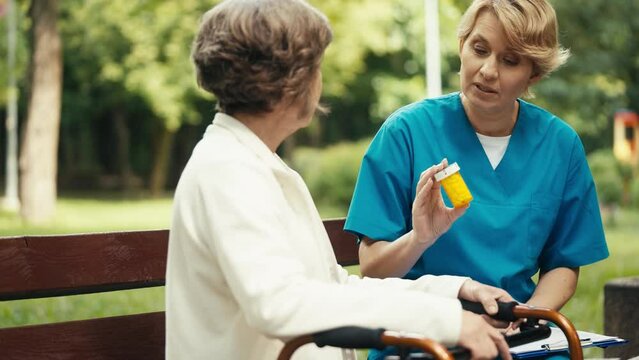Professional doctor recommending pills to senior woman with disability outdoor