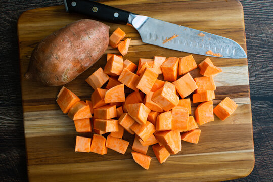 Peeled Sweet Potatoes Chopped Into Large Cubes: Prepped sweet potato chunks on a wooden cutting board