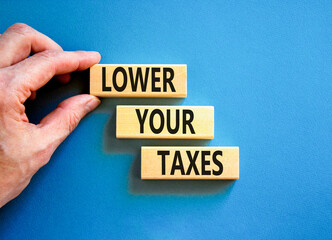Lower your taxes symbol. Concept words Lower your taxes on wooden blocks on a beautiful blue table blue background. Businessman hand. Business tax lower your taxes concept. Copy space.