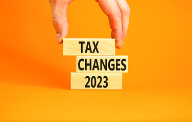 Tax changes 2023 symbol. Concept words Tax changes 2023 on wooden blocks on a beautiful orange table orange background. Businessman hand. Business Tax changes 2023 concept. Copy space.