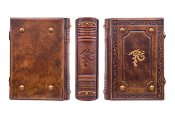 Aged brown leather book with the Eye of Horus in the center of the front cover and the book spine. The cover is embossed, gilded, have metal corners, raised ribs on the spine. 