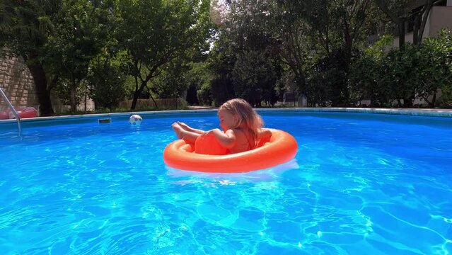 Little girl spinning on an inflatable ring in the pool