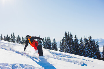 A snowboarder walks down a snowy slope in winter on the snow. Snowboarding, winter freeride