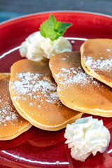 a close up portrait image of sugar covered American style pancakes served with whipped cream