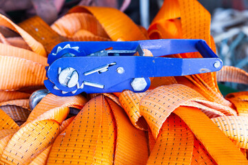The ratchet lock lies on a pile of cargo straps, close-up.