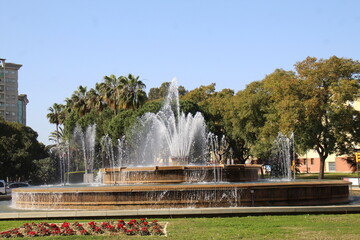 Fototapeta premium Central fountain, with several water jets and flowers on the lawn