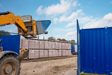 Blue dumpster auto self tipping skip with auto-lock moved by telehandler