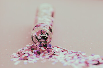 Little glass bottle with pink glitter that has fallen over and spilled glitter