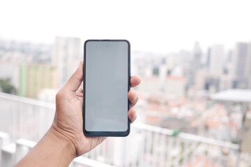 young man hand using smart phone with green screen against city buildings 