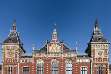 Facade of the Amsterdam Central Station against a blue sky.