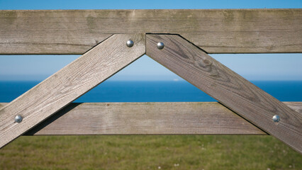 Valla de tablones de madera con forma triangular en praderas de hierba junto al mar