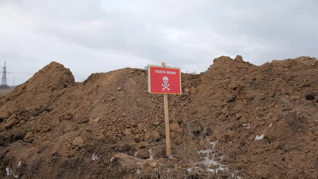 Red warning sign with the inscription Danger Mined in the middle of the field. Russian-Ukrainian war 2022.