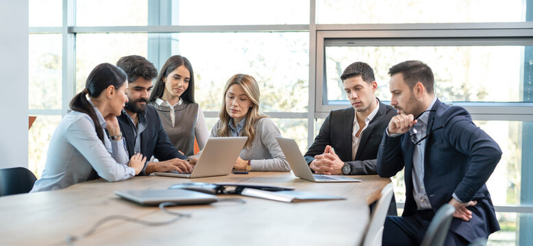 Group of business people on a meeting in office. Focused partners looking at laptops and planning new business strategy.
