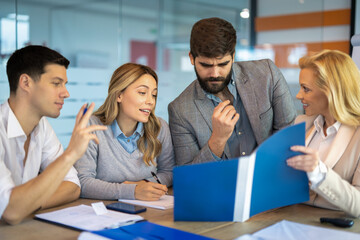 Group of business people going over paperwork together on a meeting at office.