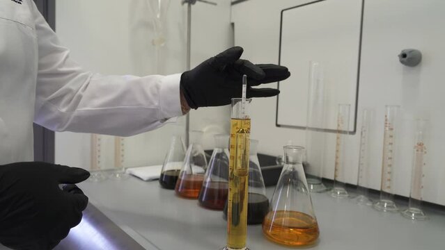 Laboratory. Test tube with oil. Density measurement. A hand in glove holds a glass float.