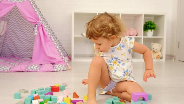 The child plays in the children's room with a wooden constructor. Selective focus.