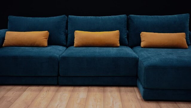 Slow shot in the office towards a dark blue couch with three long yellow pillows. 4k video