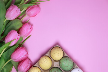 Obraz na płótnie Canvas flat lay pink Easter background with tulips and colourful eggs 