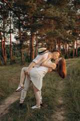 A husband kisses his wife while bending down. Lovers in the field near the trees. A boy and a girl...