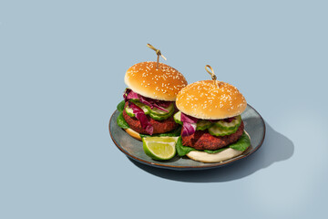 beetroot burger with lettuce and cucumber on blue background