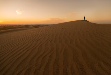 Fototapeta na wymiar Chico disfrutando del amanecer desde las dunas de Maspalomas en Gran Canaria