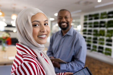 Happy diverse female and male businesspeople looking at camera in office