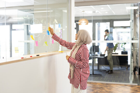 Middle-east woman in hijab in office brainstorming with post it card
