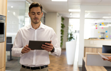 Caucasian businessman with tablet walking in office