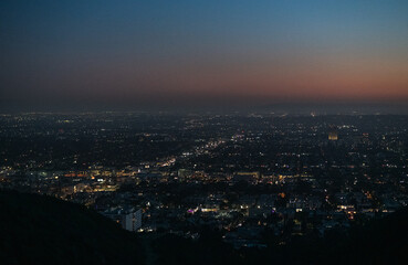 Fototapeta na wymiar Twilight in Los Angeles, seeing all of the twinkling lights on the horizon. Post sunset background view from Runyon Canyon, California