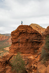 Man hiker standing on Bell Rock with incredible views within coconino national forest in Sedona Arizona USA against white cloud background.