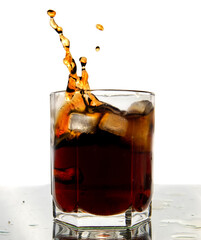 Glass of cola with splash and ice cubes on white.