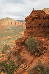 Man hiker sitting on Bell Rock with incredible views within coconino national forest in Sedona Arizona USA against white cloud background.