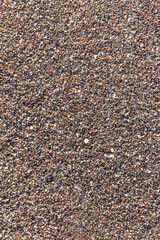 Beautiful horizontal texture of yellow sand with waves pebbles and shells is in the photo. Vertical