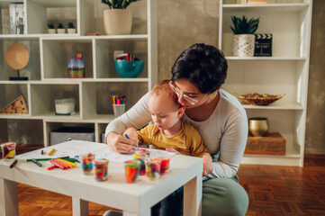 Mother and son drawing with crayons at home and having education