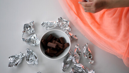 Girl putting silver candy into a ceramic bowl - 572793478