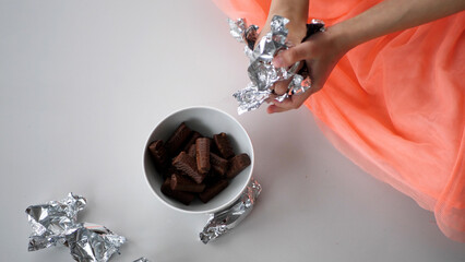 Girl putting silver candy into a ceramic bowl - 572793481