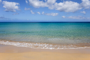 Fototapeta na wymiar Praia de areia dourada com mar calmo e transparente. Clima tropical num dia de verão.