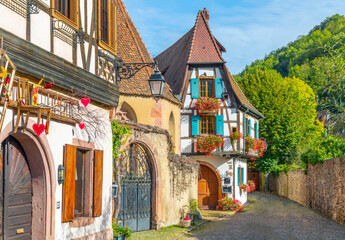 Colorful medieval half timbered medieval homes line the streets and alleys near the Weiss river canal in the historic town center of Kaysersberg Vignoble, France in the Alsace region.	