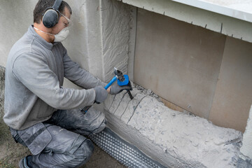 Man Creating Window by Demolishing Concrete House Wall