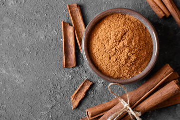 Cinnamon sticks and cinnamon powder on dark rustic background, healthy spice, (Cinnamomum)