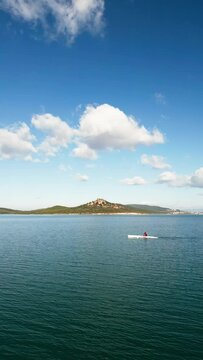 Aerial drone bird's eye view video of sport canoe operated by young woman in emerald clear waters. High quality 4k footage