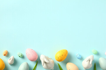 Happy Easter banner template. Frame border made of Easter Eggs, bunny, tulips on light blue table. Flat lay, top view.