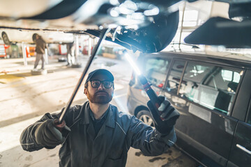 High angle shot of a mechanic doing an undercarriage inscpection. Repair shop concept. High quality photo